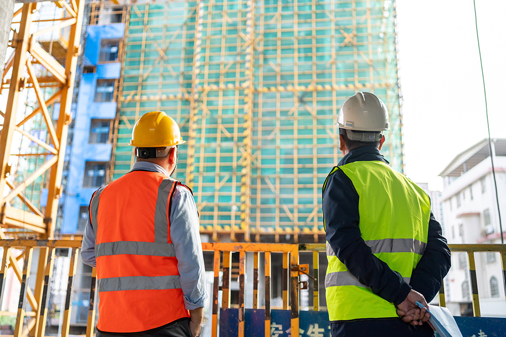 backs of two contractors looking out at a new build in city