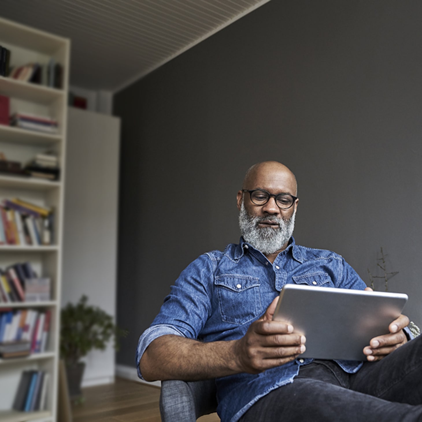 midaged Black man with beard kicking back with an ipad