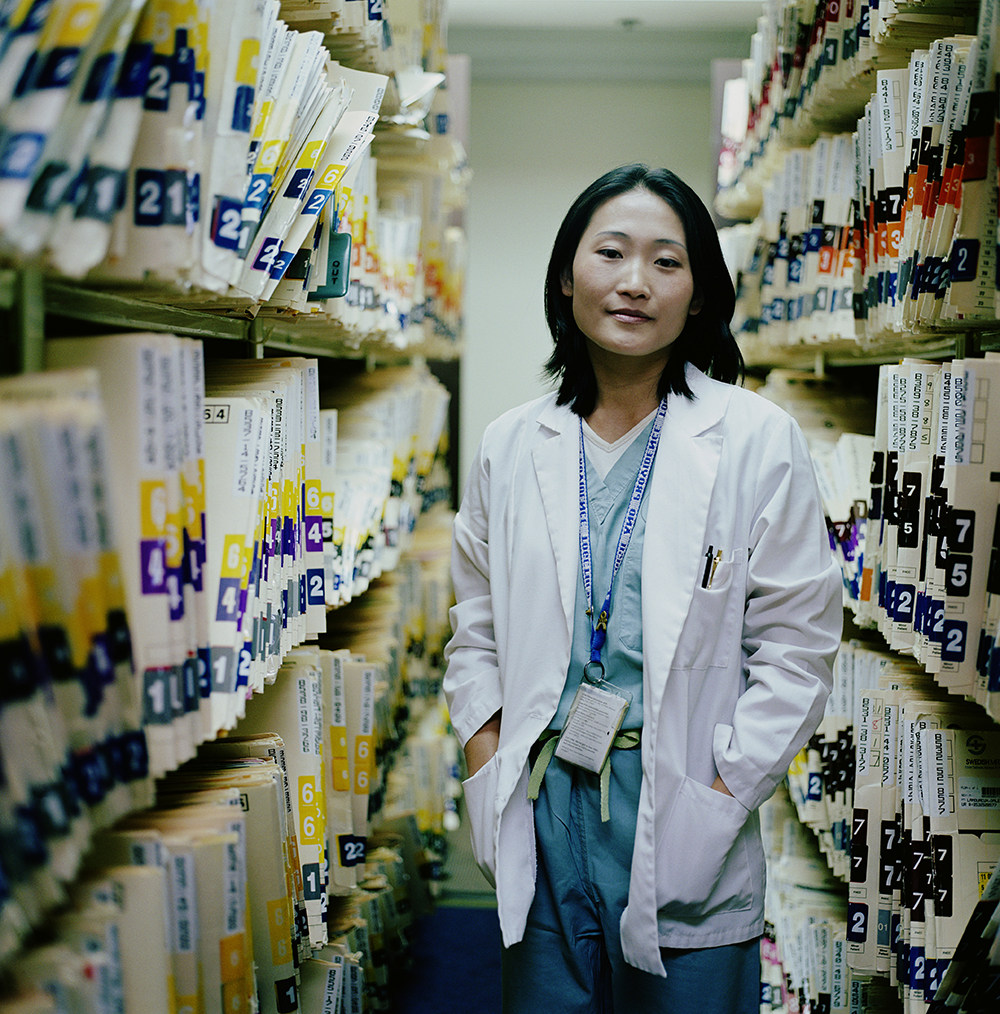 female presenting medical employe standing by files