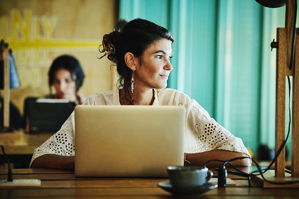 Woman in white sitting at desk on laptop