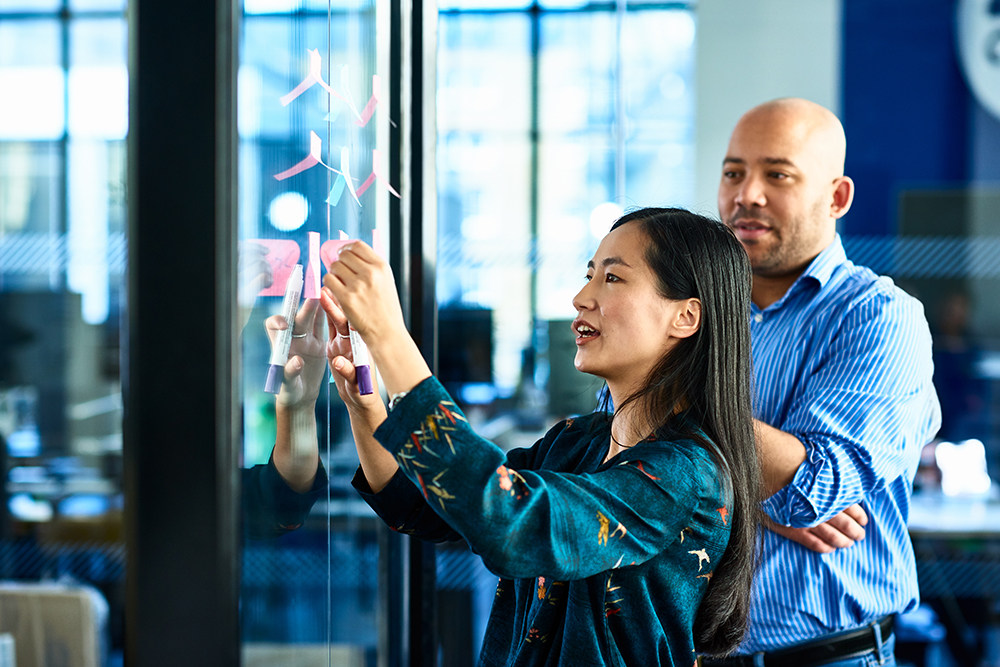 man and woman problem solving with post-its
