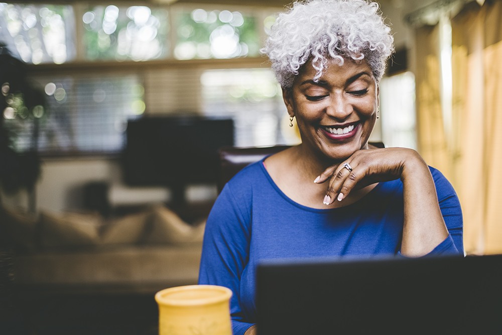 Black woman with white hair in blue top on her computer