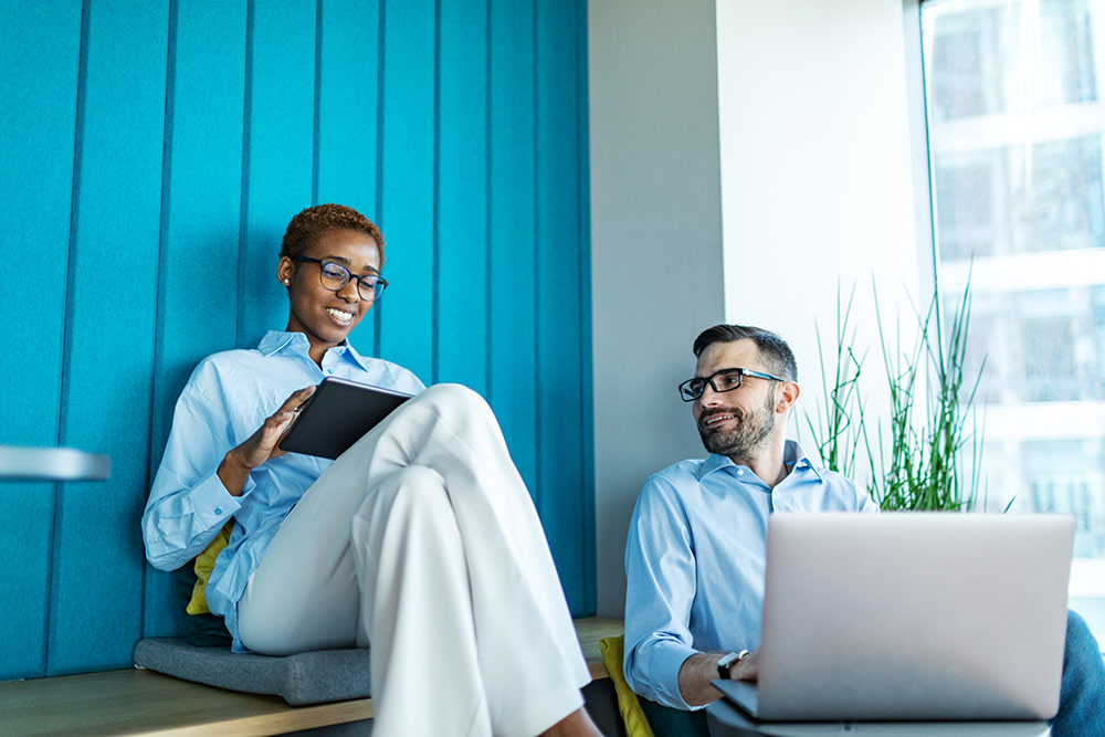 Black woman and white man, both in blue shirts and glasses, working together outside