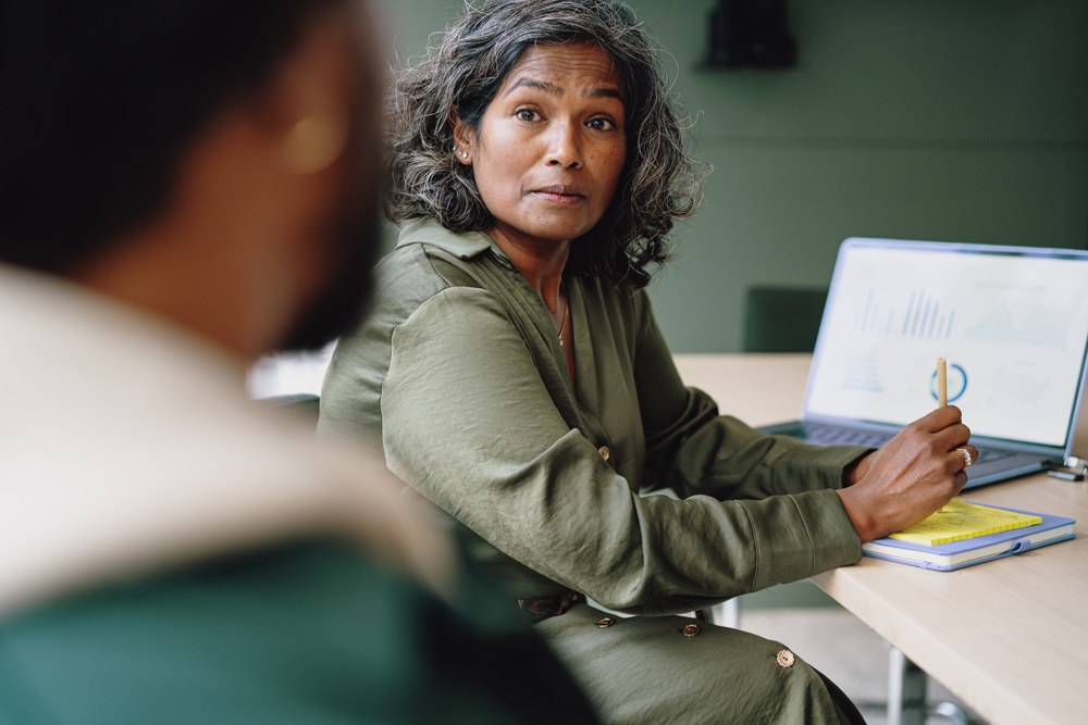 Lady in green looking at man with pen in her hand