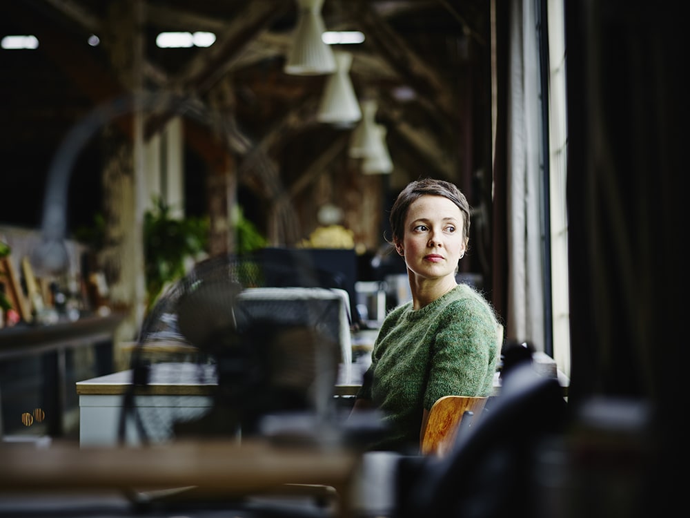 woman in green at office looking out window