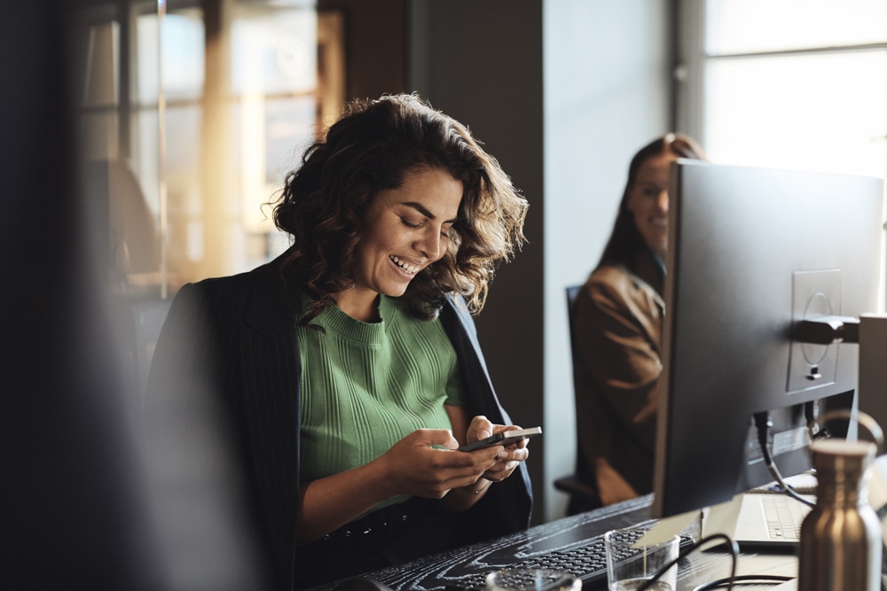woman in nacy blazer and green top working at her desk