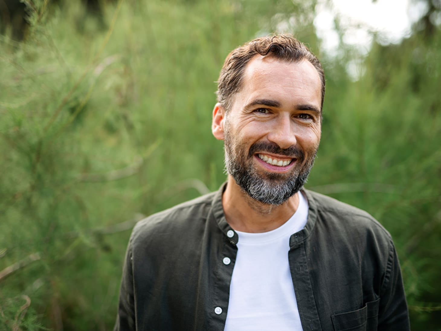 close-up of bearded white man in front of greenery