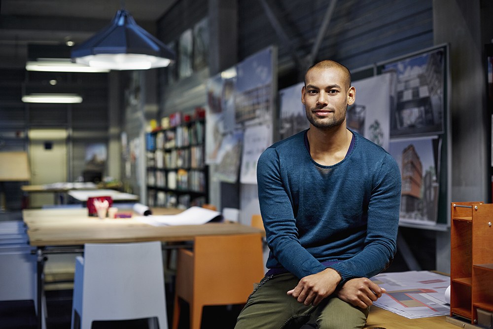 Man in blue sitting on desk
