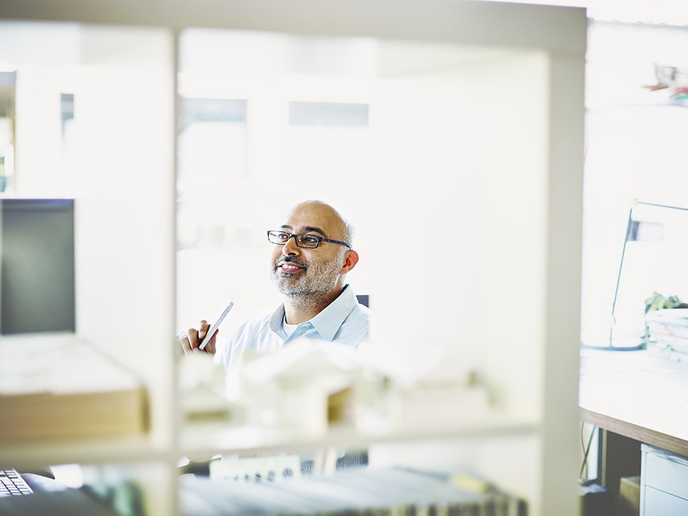 Man smiling in office on his desk