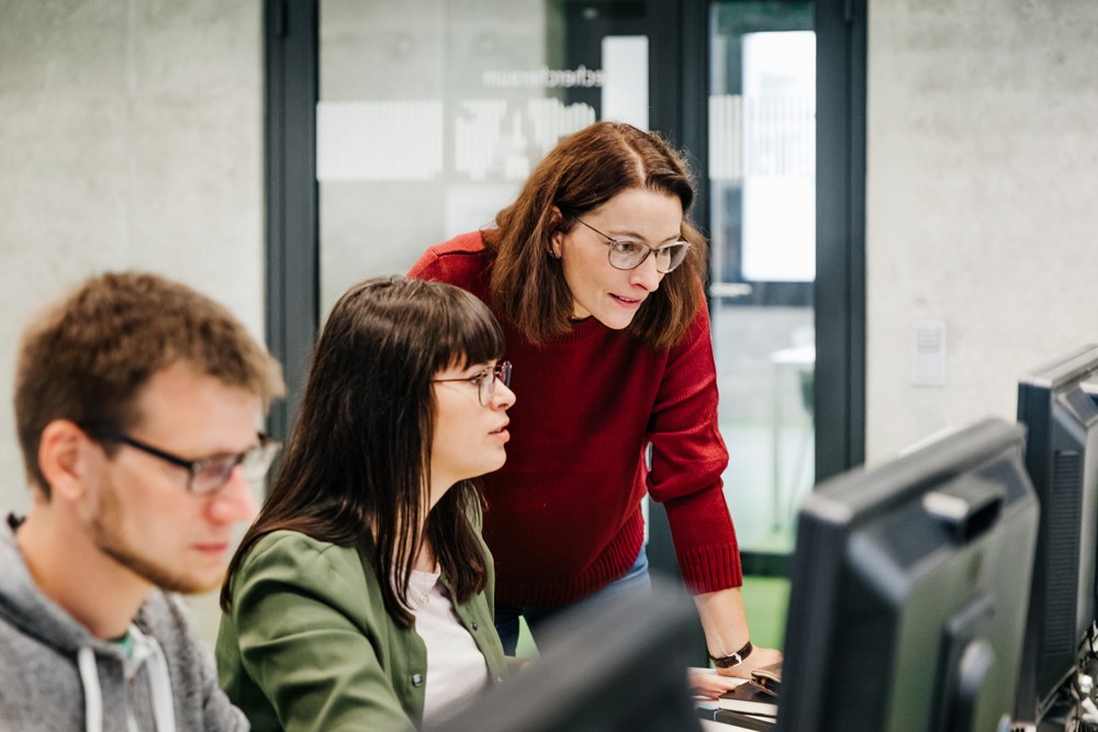 Employees around computer assisting each other