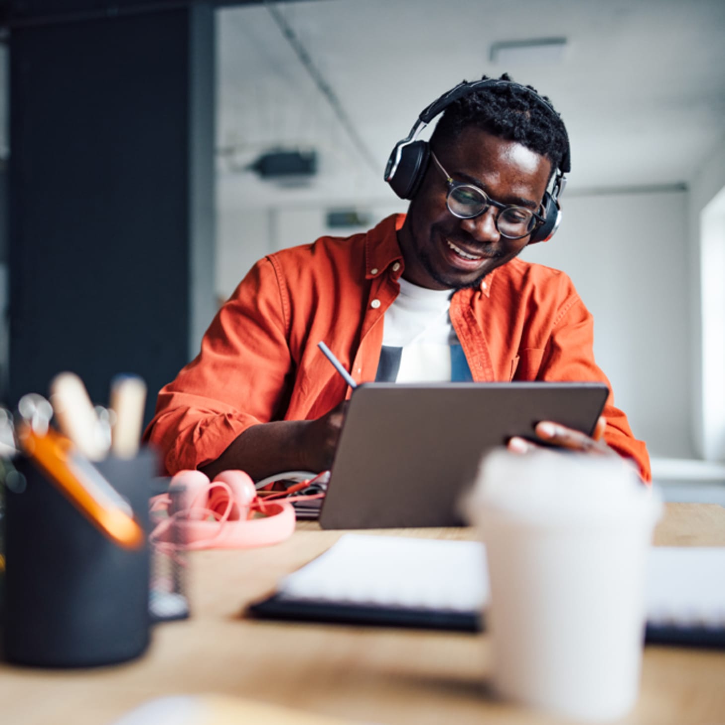 Black man working on ipad with stylus and wearing headphones
