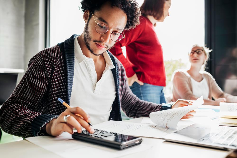 Employee with glasses on looking a papers and calculator
