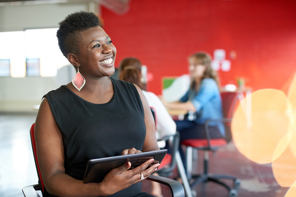 Woman in black smiling holding tablet