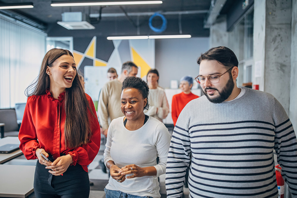 Teammates talking and laughing walking through office