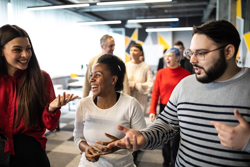 three young coworkers walking and laughing together in office hall