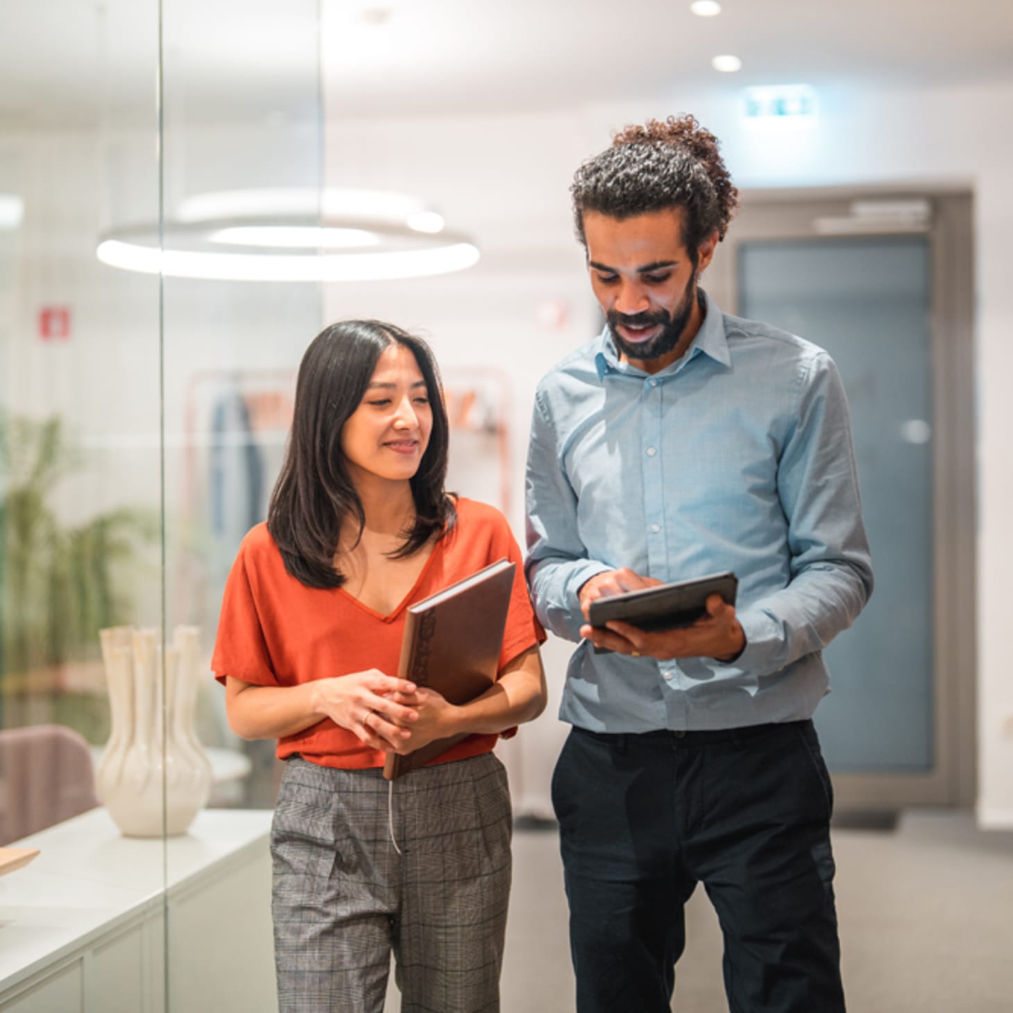 woman and man walking in an office together with ipads