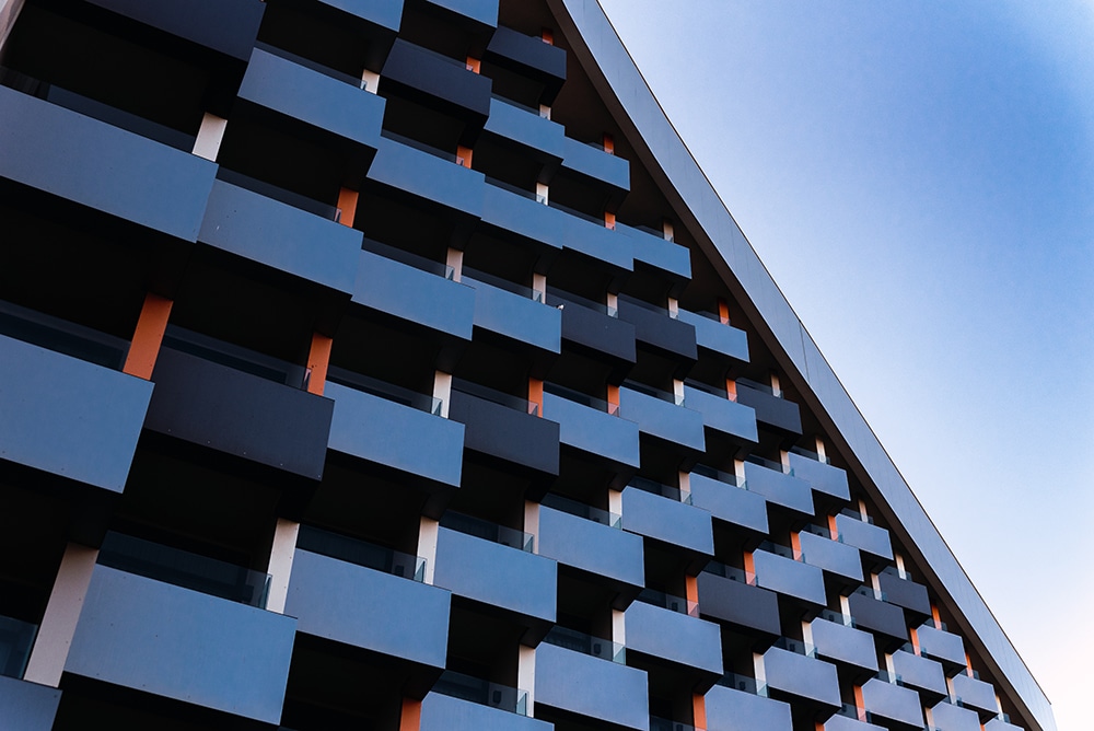 upshot of blue building with orange accents, against the blue sky