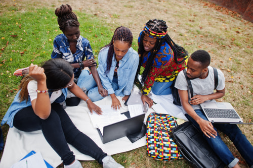 Group of five college students looking at a laptop.