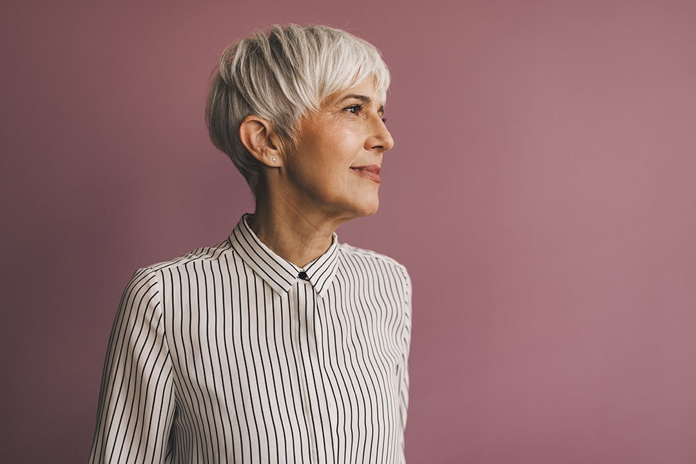midaged white woman with white hair looking to the right on mauve background