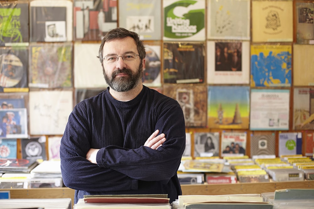 bearded male record shop owner standing in the store