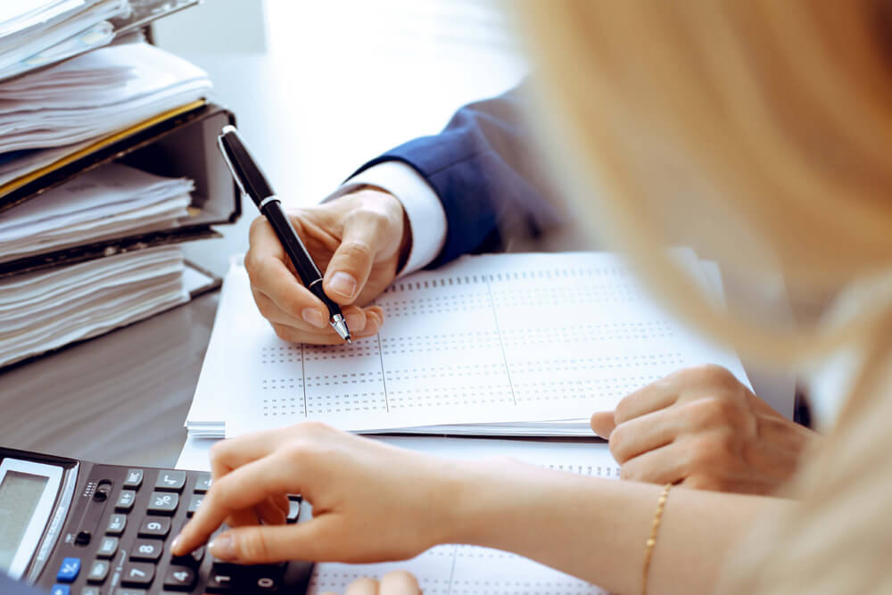 Hand using a calculator & hand writing with a pen